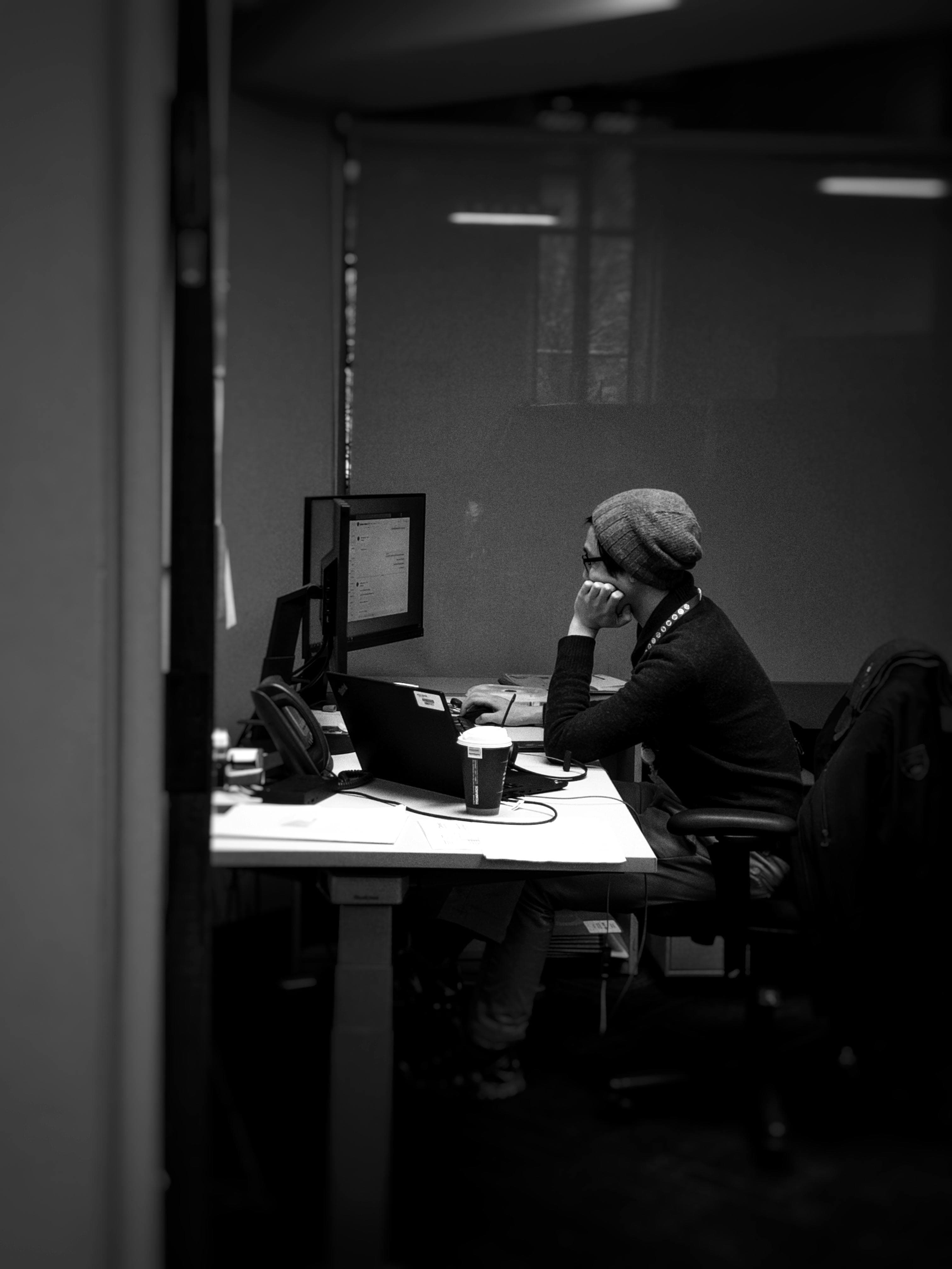 A focused founder working at a desk with a computer and notebook.