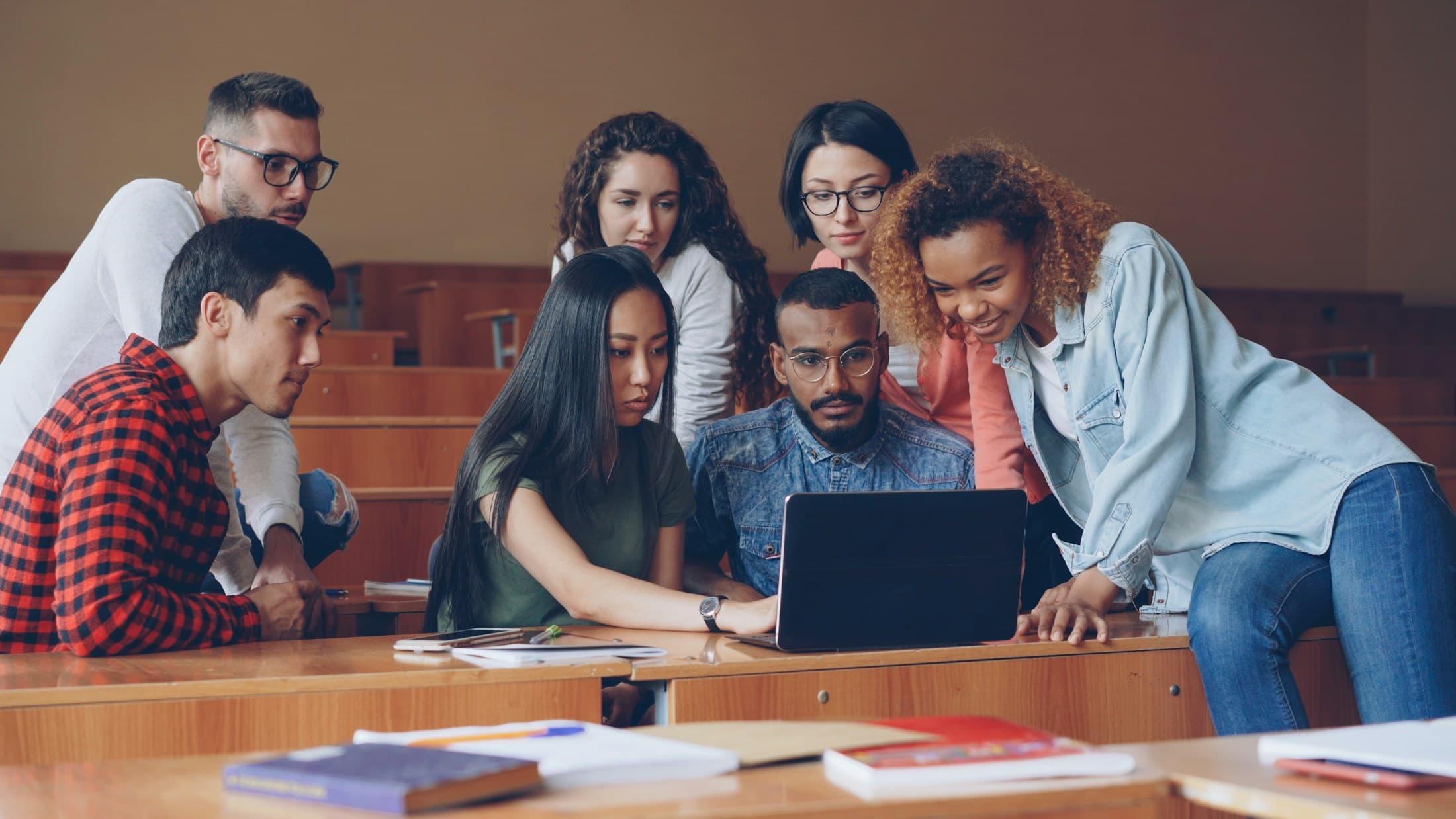 Students gathered around a laptop during a casual workshop.